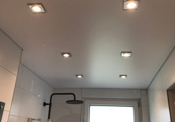 Entspannendes Badezimmer mit weißer satinierter Spanndecke und stilvollen Einbaustrahlern aus Klarglas